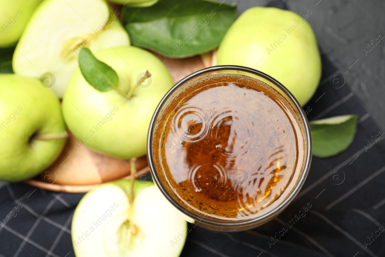 Fresh cider in glass and apples on black table, flat lay Photo of Fresh cider in glass and apples on black table, flat lay