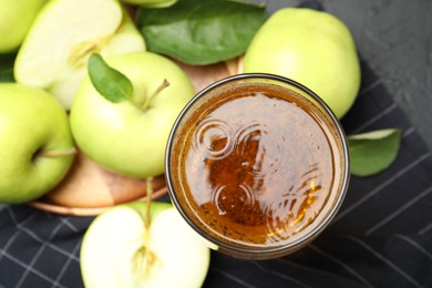 Photo of Fresh cider in glass and apples on black table, flat lay