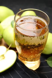 Photo of Fresh cider in glass and apples on table, closeup