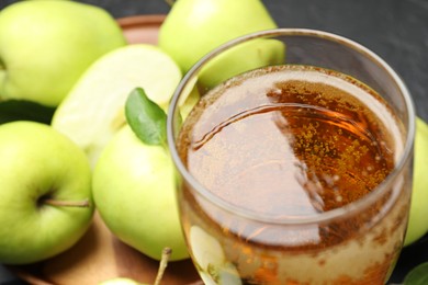 Photo of Fresh cider in glass and apples on table, closeup