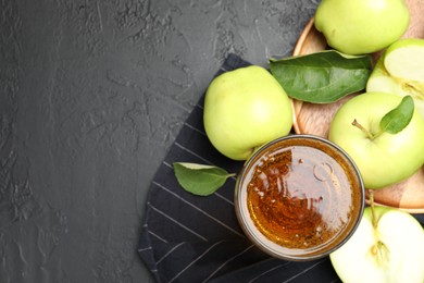 Photo of Fresh cider in glass and apples on black table, flat lay. Space for text