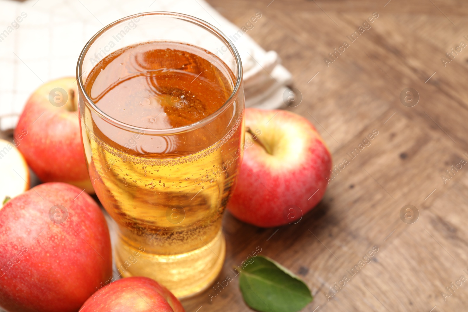 Fresh cider in glass and apples on wooden table, closeup. Space for text Photo of Fresh cider in glass and apples on wooden table, closeup. Space for text