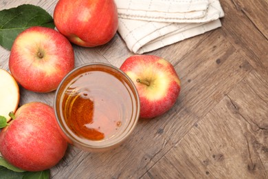 Photo of Fresh cider in glass and apples on wooden table, flat lay. Space for text