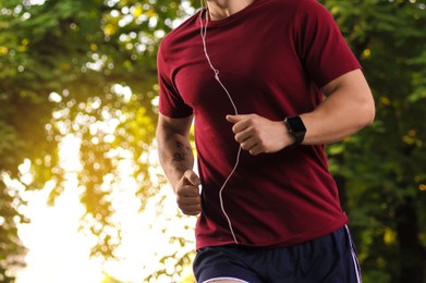 Photo of Athletic young man in sportswear running outdoors, closeup