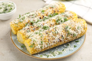 Photo of Tasty grilled corncobs with parsley and cheese on light table, closeup