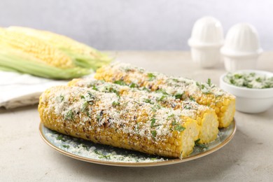 Photo of Tasty grilled corncobs with parsley and cheese on light table, closeup