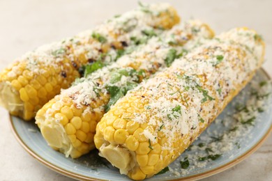 Photo of Tasty grilled corncobs with parsley and cheese on light table, closeup