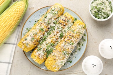 Photo of Tasty grilled corncobs with parsley and cheese on light table, flat lay