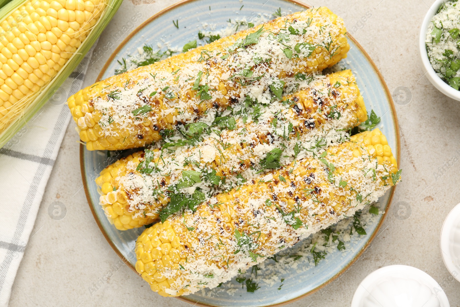 Photo of Tasty grilled corncobs with parsley and cheese on light table, flat lay