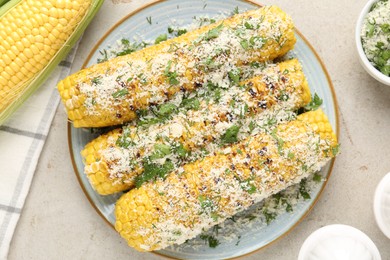 Photo of Tasty grilled corncobs with parsley and cheese on light table, flat lay