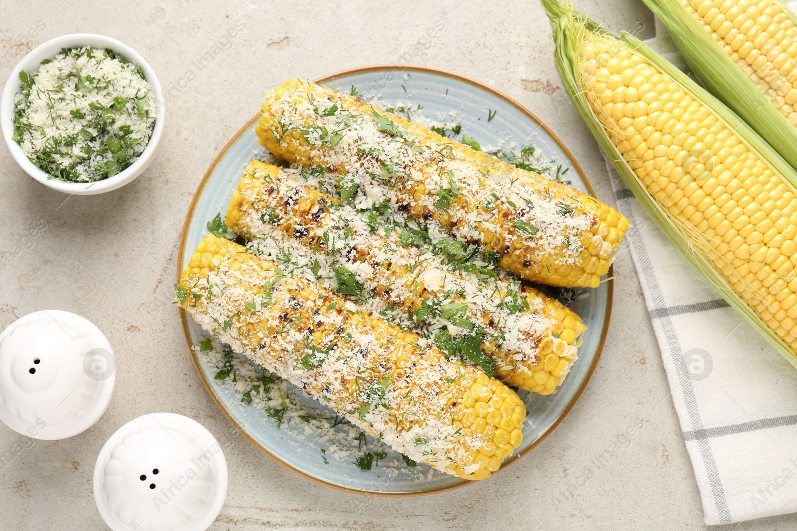 Photo of Tasty grilled corncobs with parsley and cheese on light table, flat lay