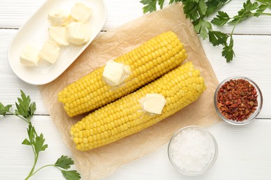 Photo of Tasty boiled corncobs with butter, parsley and spices on white wooden table, flat lay