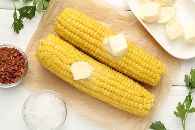 Photo of Tasty boiled corncobs with butter, parsley and spices on white wooden table, flat lay