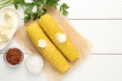 Photo of Tasty boiled corncobs with butter, parsley and spices on white wooden table, flat lay. Space for text