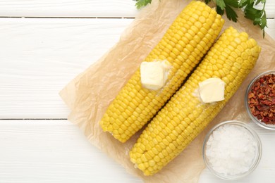 Photo of Tasty boiled corncobs with butter, parsley and spices on white wooden table, flat lay. Space for text