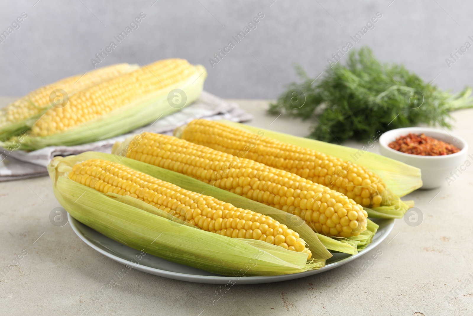 Photo of Tasty boiled corncobs on light table, closeup
