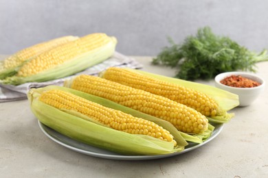 Photo of Tasty boiled corncobs on light table, closeup