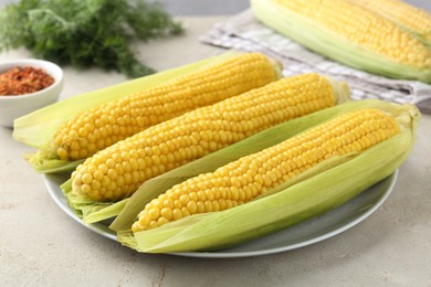 Photo of Tasty boiled corncobs on light table, closeup