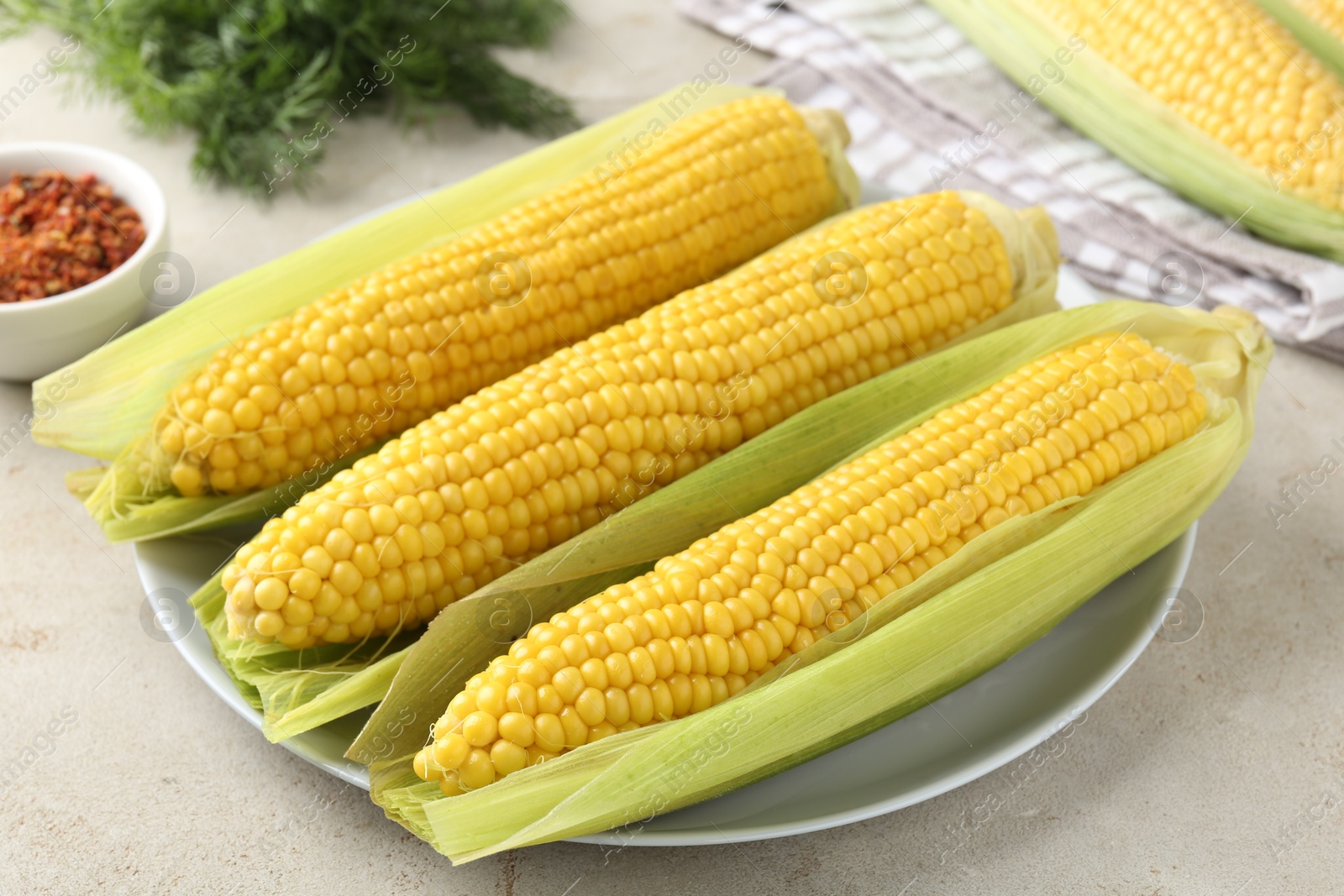 Photo of Tasty boiled corncobs on light table, closeup
