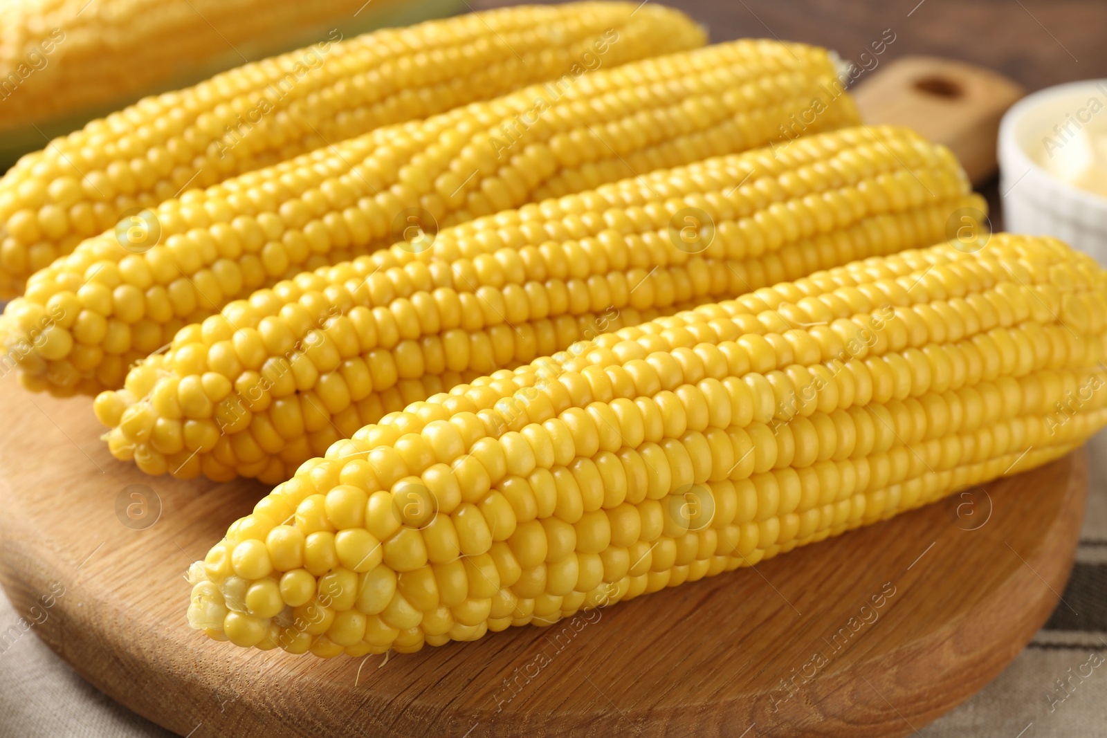 Photo of Tasty boiled corncobs on wooden table, closeup