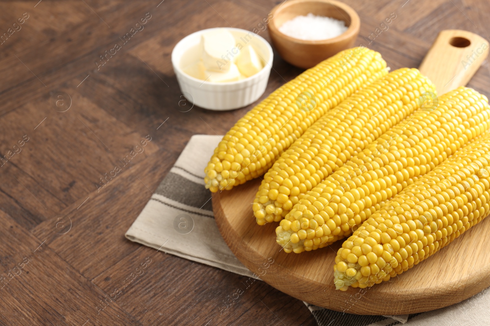 Tasty boiled corncobs, salt and butter on wooden table, closeup. Space for text Photo of Tasty boiled corncobs, salt and butter on wooden table, closeup. Space for text
