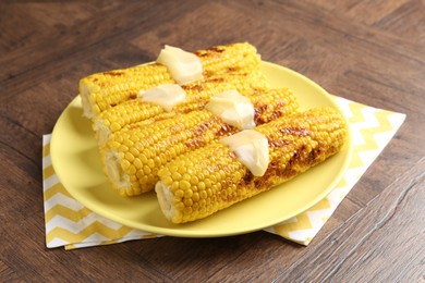 Photo of Tasty grilled corncobs with sauce on wooden table