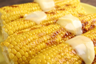Photo of Tasty grilled corncobs with sauce on table, closeup