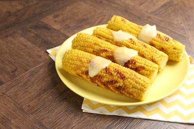 Photo of Tasty grilled corncobs with sauce on wooden table, closeup