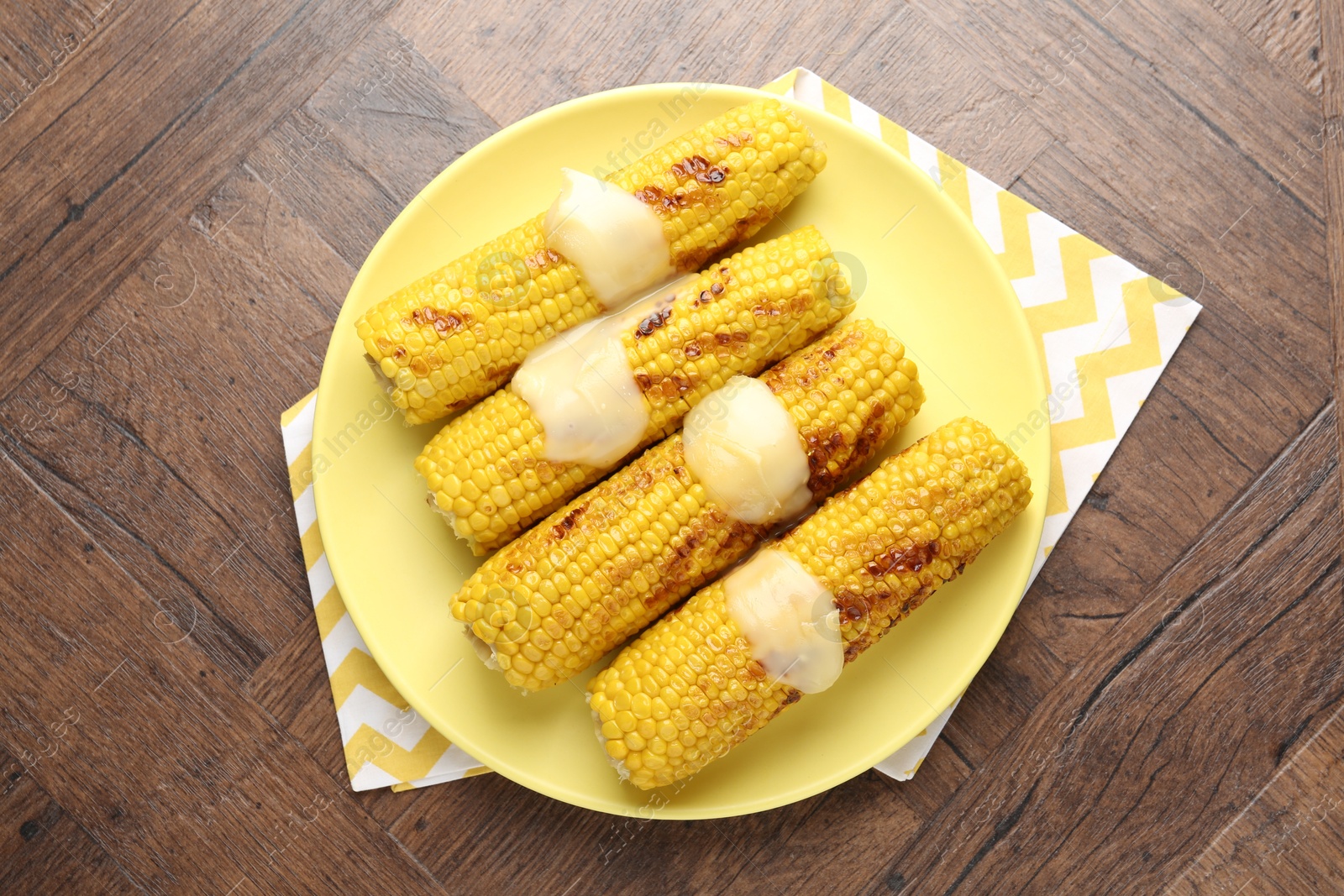 Tasty grilled corncobs with sauce on wooden table, top view Photo of Tasty grilled corncobs with sauce on wooden table, top view