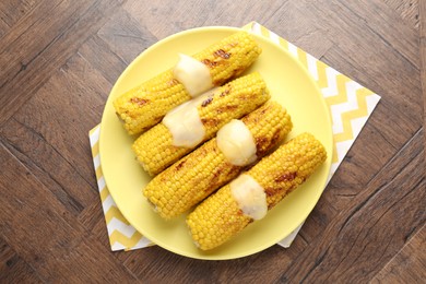 Photo of Tasty grilled corncobs with sauce on wooden table, top view