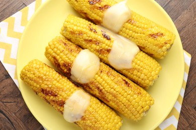 Photo of Tasty grilled corncobs with sauce on wooden table, top view