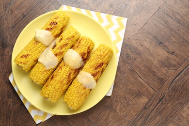 Photo of Tasty grilled corncobs with sauce on wooden table, top view. Space for text