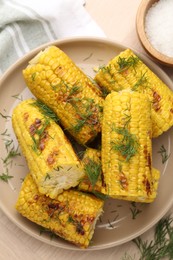Photo of Pieces of tasty grilled corncobs with dill on wooden table, flat lay