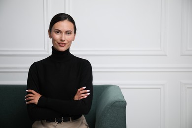 Photo of Beautiful woman on sofa near white wall. Space for text