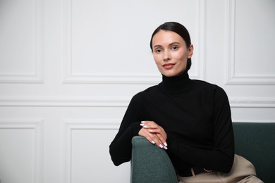 Photo of Beautiful woman on sofa near white wall. Space for text