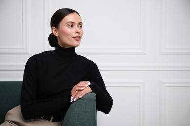 Photo of Beautiful woman on sofa near white wall. Space for text