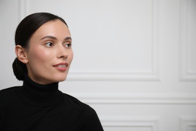 Photo of Portrait of beautiful woman near white wall. Space for text