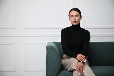 Photo of Beautiful woman on sofa near white wall. Space for text