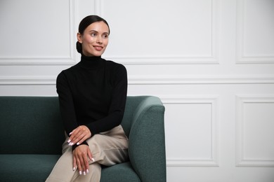 Photo of Beautiful woman on sofa near white wall. Space for text