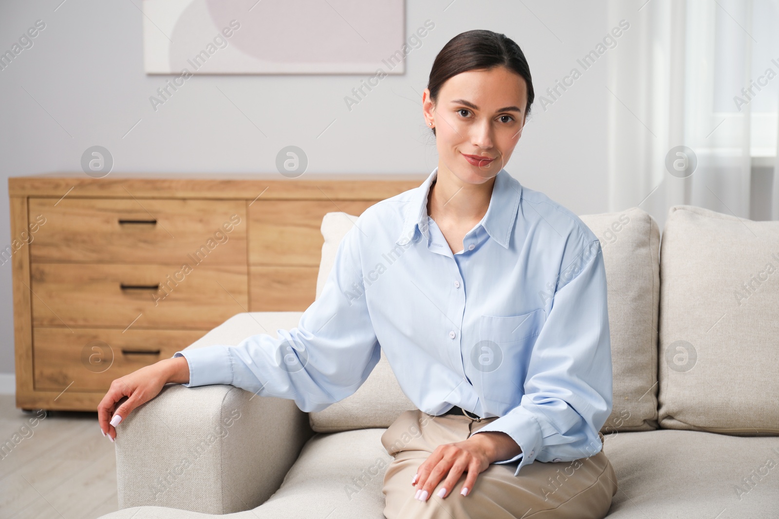 Photo of Elegant woman sitting on sofa at home. Space for text