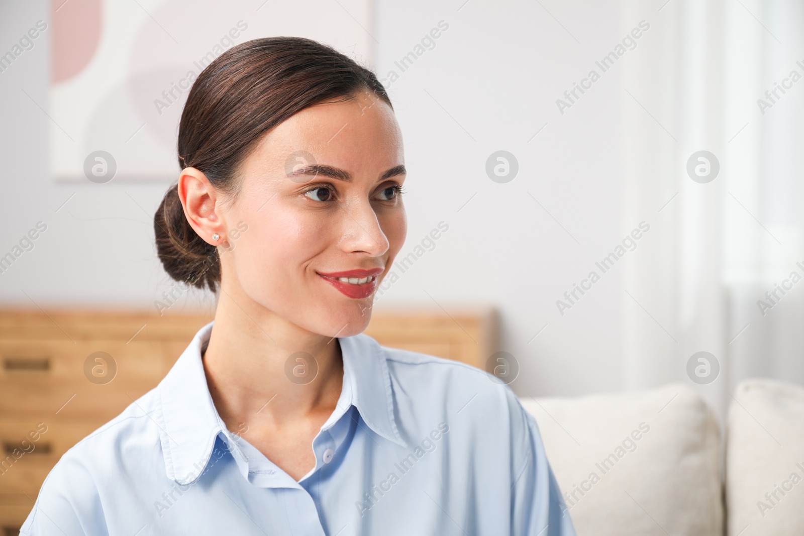 Photo of Elegant woman sitting on sofa at home. Space for text