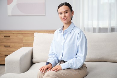 Photo of Elegant woman sitting on sofa at home