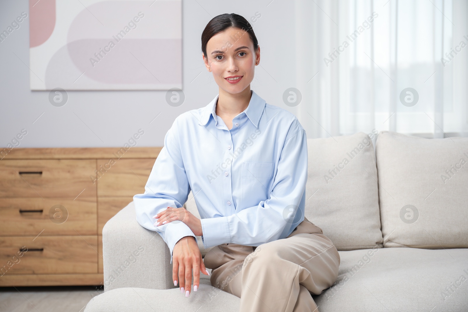Photo of Elegant woman sitting on sofa at home