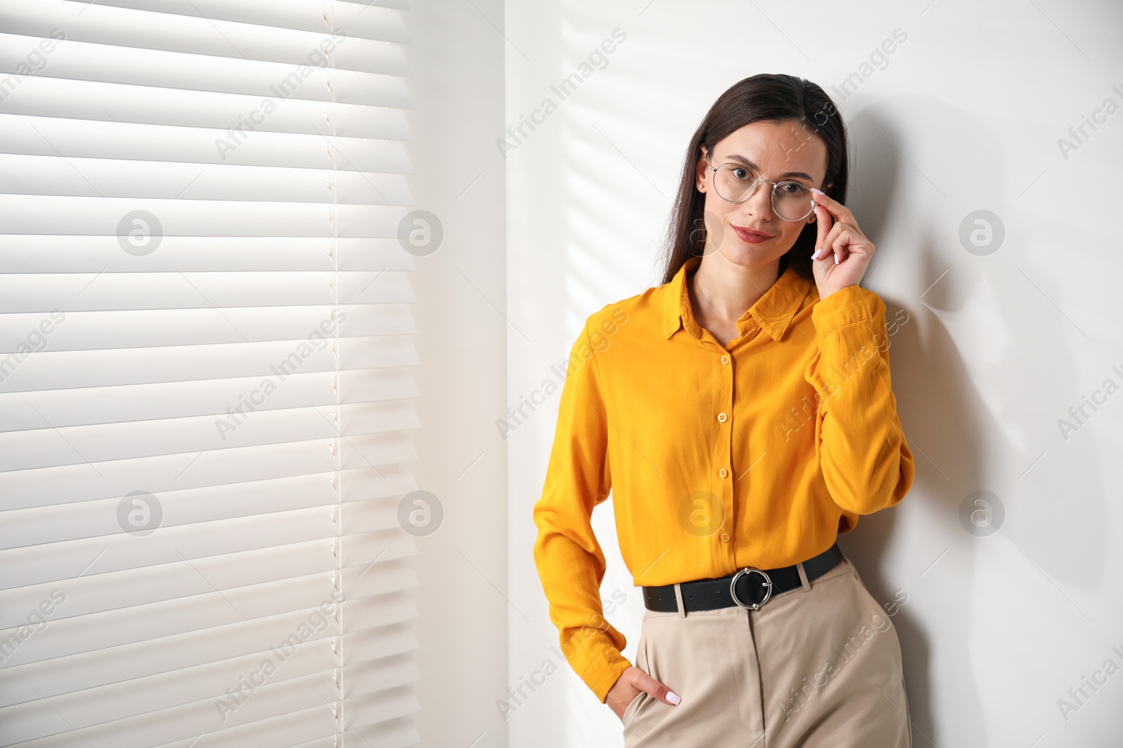 Photo of Beautiful young woman near white wall indoors. Space for text