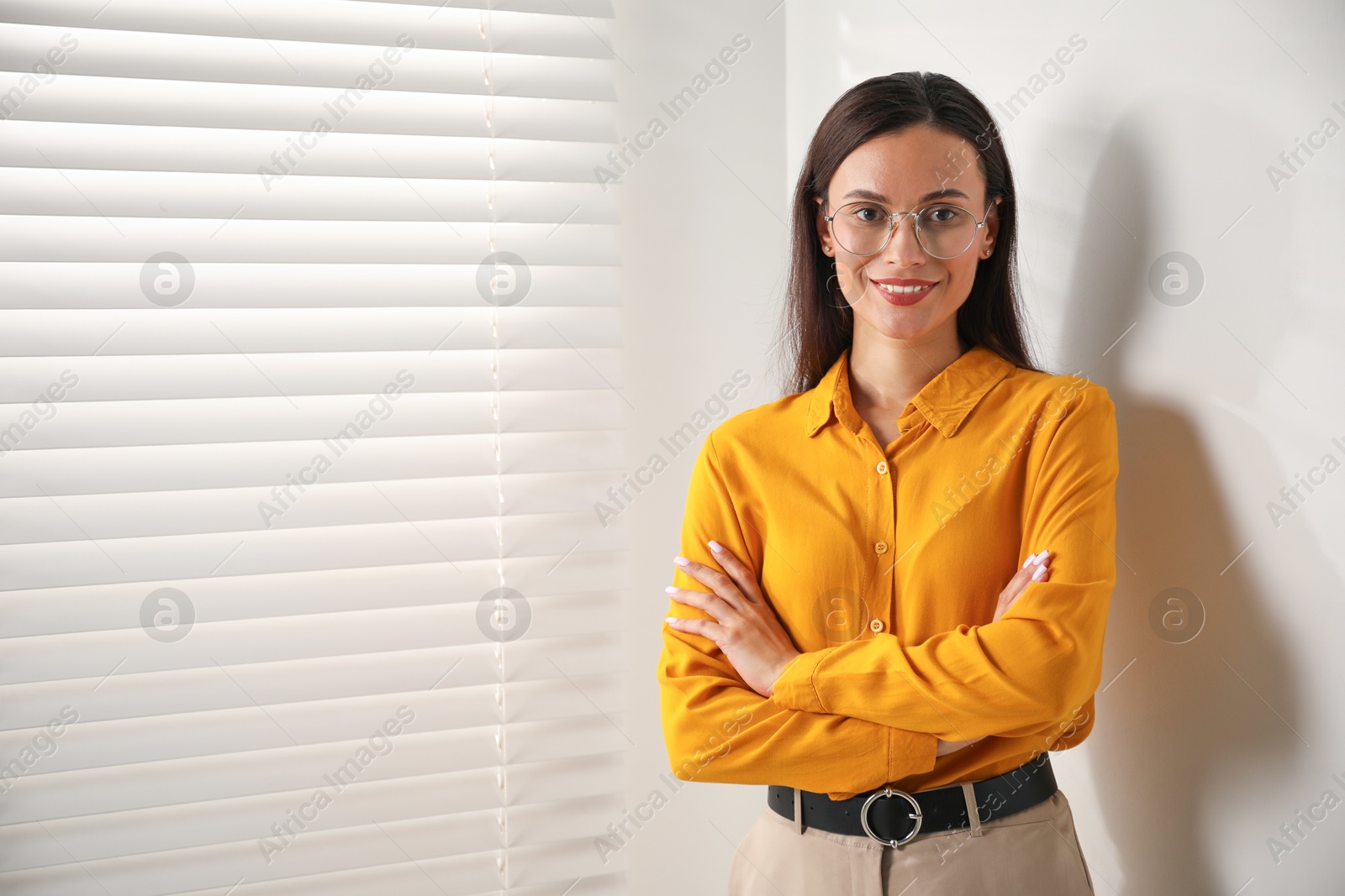 Photo of Beautiful young woman near white wall indoors. Space for text