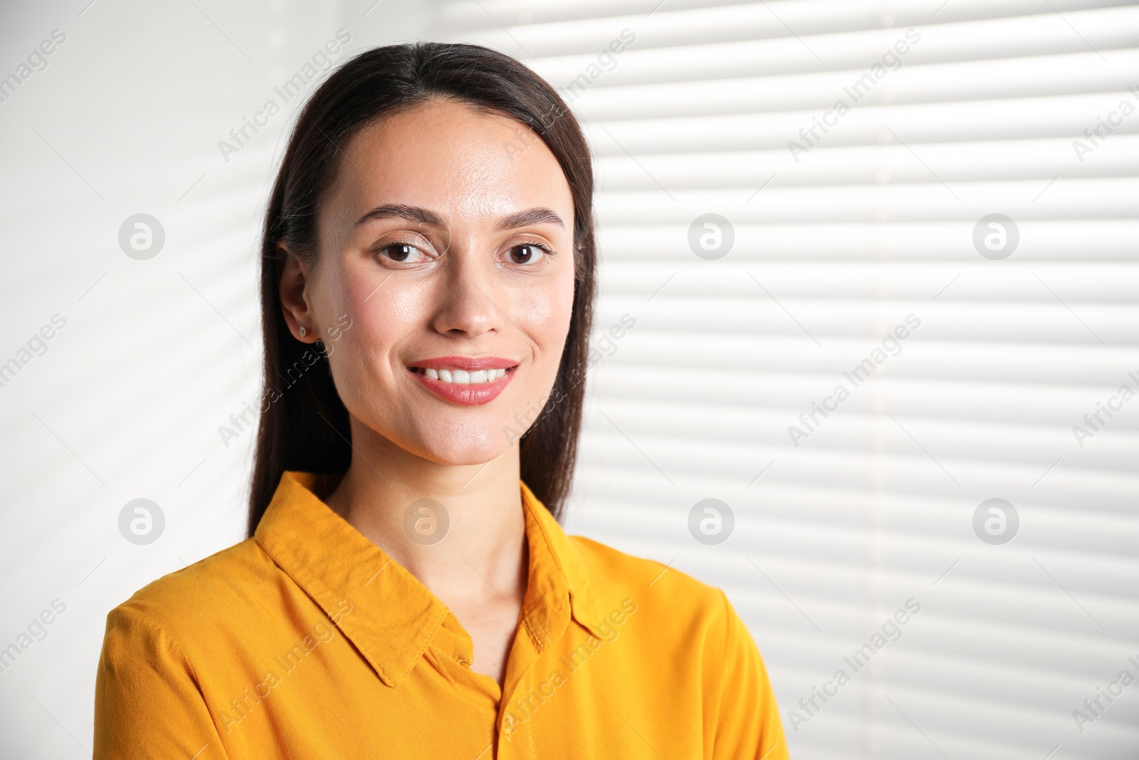 Photo of Beautiful young woman near white wall indoors. Space for text