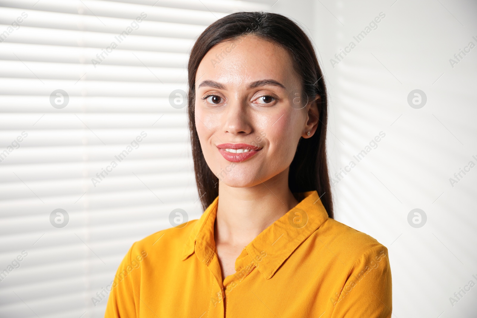 Photo of Beautiful young woman near white wall indoors