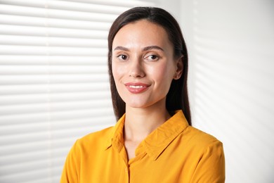 Photo of Beautiful young woman near white wall indoors