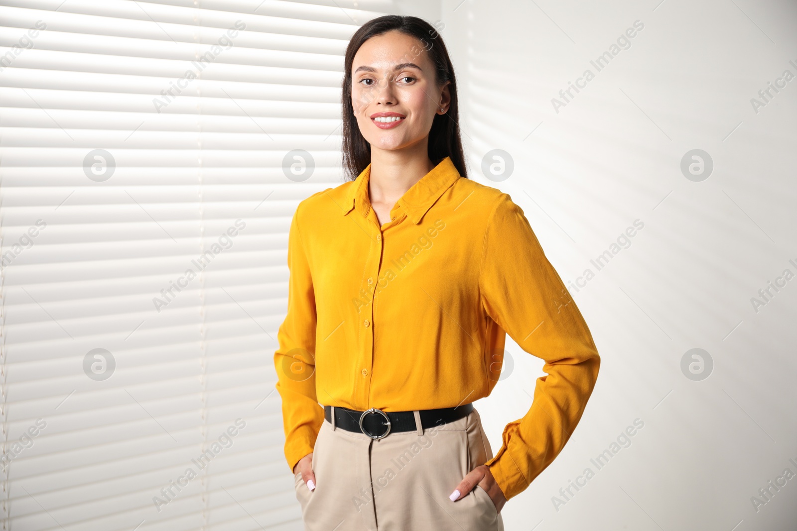 Photo of Beautiful young woman near white wall indoors