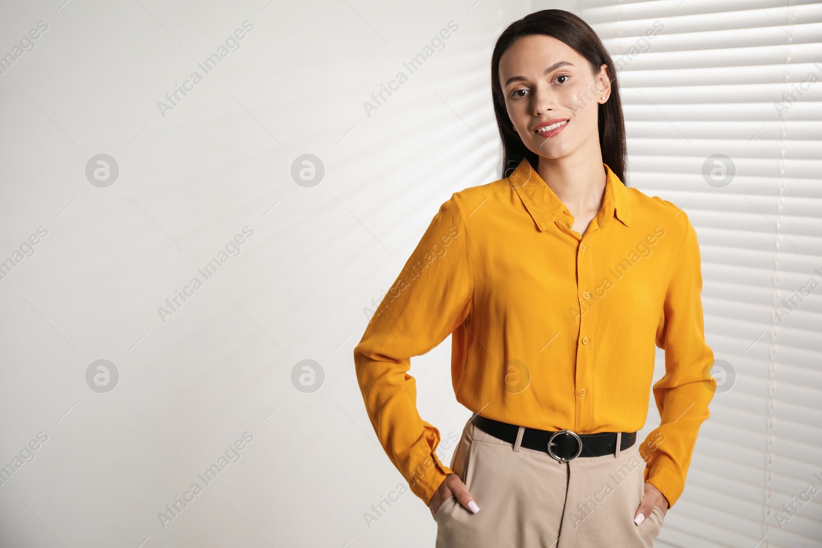 Photo of Beautiful young woman near white wall indoors. Space for text